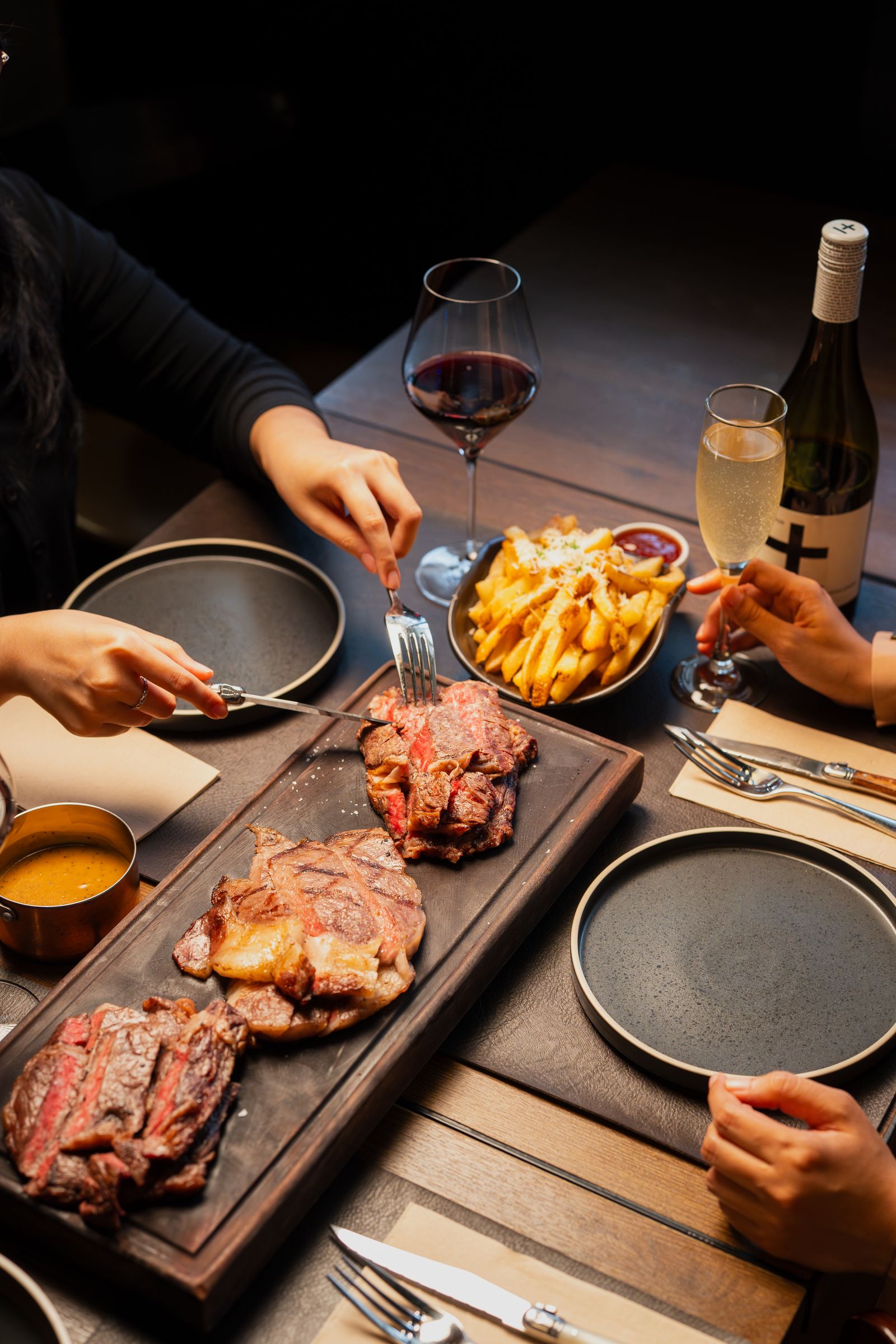 A shared feast board of steak and fries mid-service